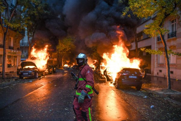 A firefighter looks on as cars are burning
