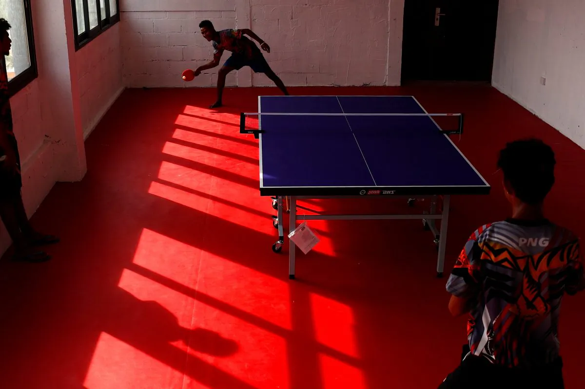 Papua New Guinea table tennis players Goada Elly and David Thomas play on a table during a practice session at a Beijing-funded facility in central Port Moresby, Papua New Guinea on Nov. 19, 2018. (David Gray/Reuters)