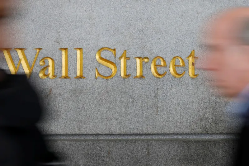 People walk by a Wall Street sign close to the New York Stock Exchange (NYSE) in New York, U.S., April 2, 2018. REUTERS/Shannon Stapleton
