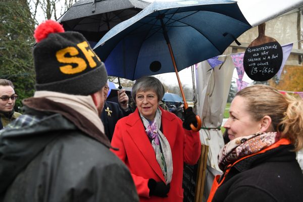 Theresa May shelters under umbrella