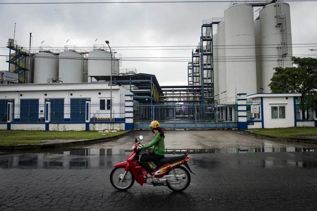 A Vietnamese woman drives a motorbike past a factory in an industrial zone in the central Vietnamese city of Danang on Nov. 10, 2017. (Lillian Suwanrumpha/AFP/Getty Images)