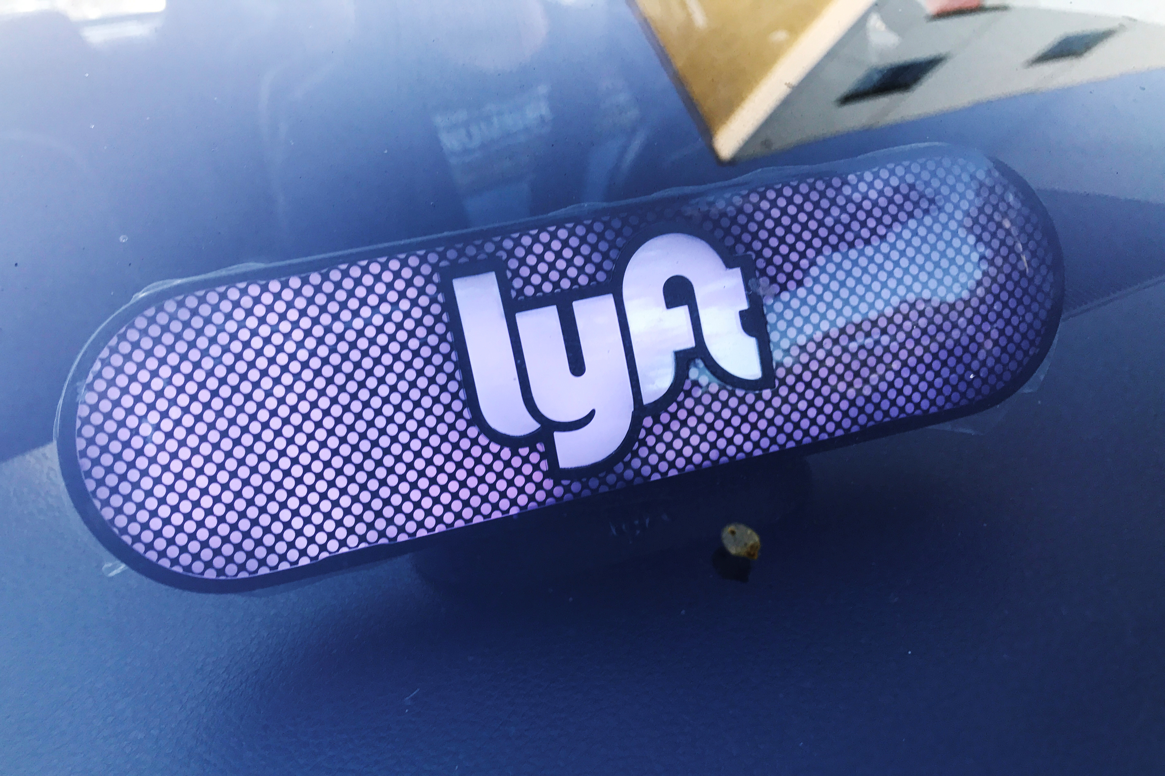 An illuminated sign appears in a Lyft ride-hailing car