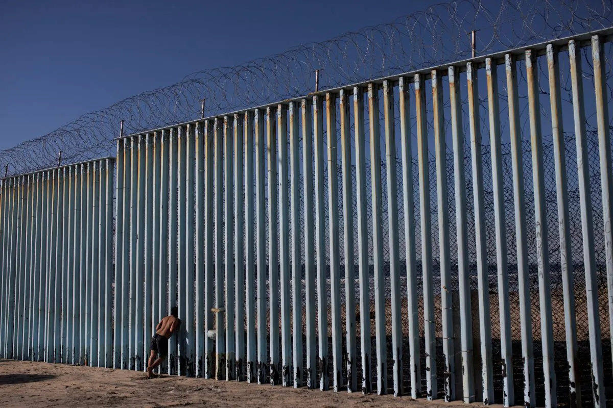 A migrant from Honduras looks through the border wall on the beach of Tijuana, Mexico, on Dec. 3, 2018. (Alkis Konstantinidis/Reuters)