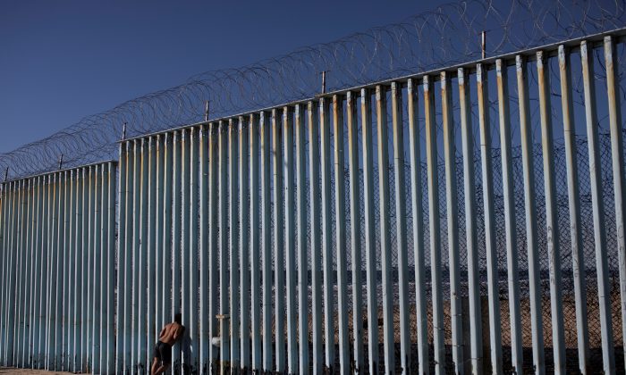 A migrant from Honduras looks through the border wall on the beach of Tijuana, Mexico, on Dec. 3, 2018. (Alkis Konstantinidis/Reuters)