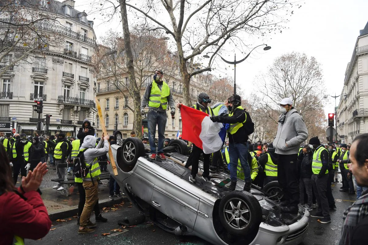 Demonstrators stand on a destroyed car during a protest of yellow vests against rising oil prices and living costs, near the Champs Elysees in Paris, on December 1, 2018. - (Alain Jocard/AFP/Getty Images)