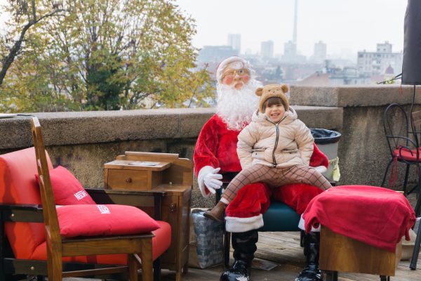 Child sits on fake Santa lap in front of view of Zagreb