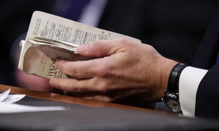 Supreme Court Justice Brett Kavanaugh thumbs through a well-worn, pocket-sized copy of the U.S. Constitution as he testifies before the Senate Judiciary Committee on the second day of his confirmation hearing on Capitol Hill, Sept. 5, 2018, in Washington, DC. (Chip Somodevilla/Getty Images)
