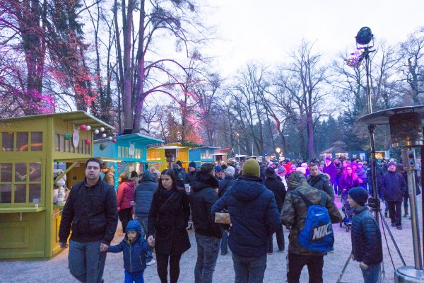 Crowds walk among trees and Christmas market stands at Advent in Maksimir Park Zagreb