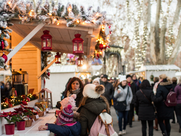 Mother and little girls look at Christmas market stand