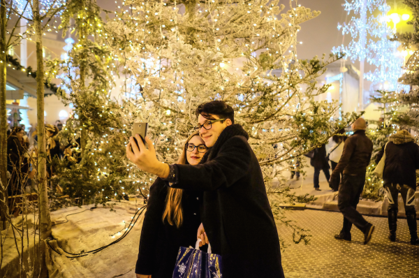 Young couple takes selfie in Christmas square with snow