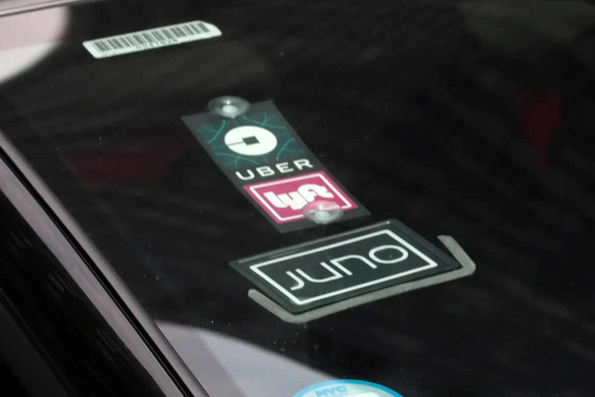 The Uber, Lyft and Juno logos are seen on a car as it drive up 6th Avenue in New York City, July 27, 2018. (Mike Segar/File Photo/Reuters)