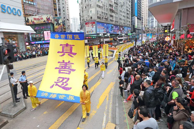 Falun Gong practitioners hold up yellow banners in a parade in Hong Kong on Dec. 9, 2018. (Li Yi/The Epoch Times)