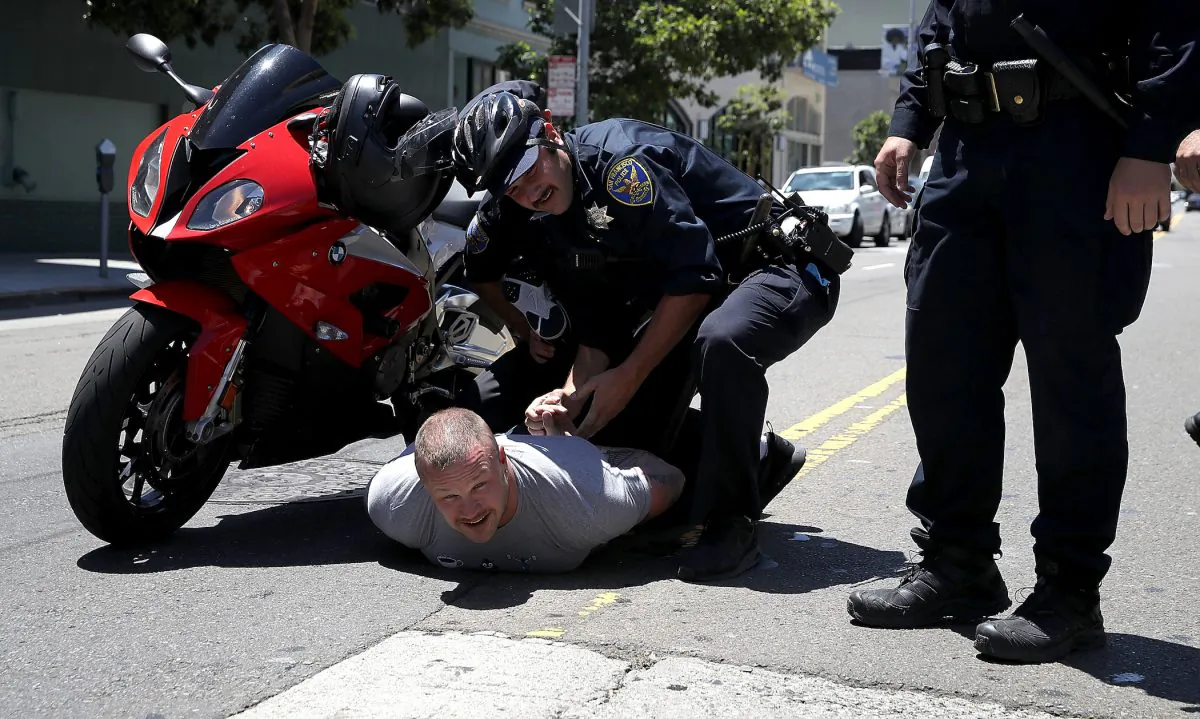 San Francisco police detain a man who rode a motorcycle through dozens of health care activists who were blocking a street in San Francisco, Calif., on June 21, 2017. (Justin Sullivan/Getty Images)