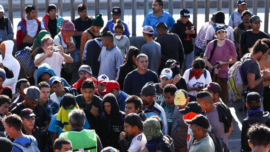 Migrants walk back to their camp after a failed attempt to rush the U.S. border and enter illegally, just west of the San Ysidro crossing in Tijuana, Mexico, on Nov. 25, 2018. The fence in the background is not the border, it's a secondary fence on the Mexico side. (Charlotte Cuthbertson/The Epoch Times)