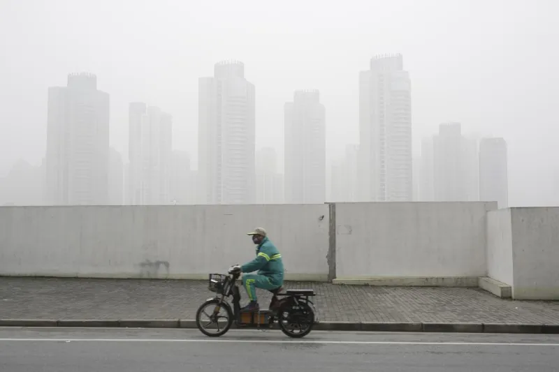 A man wearing a face mask rides an electric bicycle near the financial district of Pudong amid heavy smog in Shanghai, China on Dec. 23, 2015. (Aly Song/Reuters)