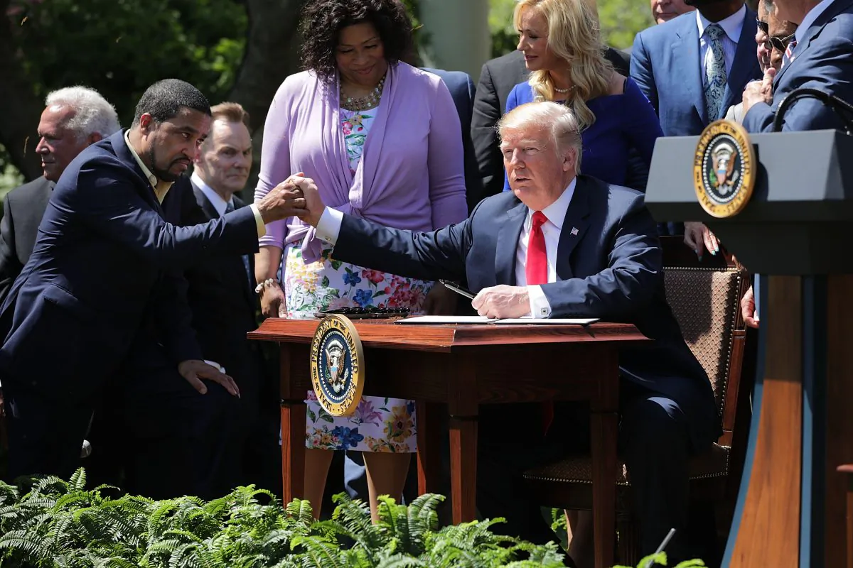 President Donald Trump shakes hands with Pastor Darrell Scott, co-founder of the New Spirit Revival Center, before Trump signs an executive order during an event in the Rose Garden to mark the National Day of Prayer at the White House on May 3, 2018. (Chip Somodevilla/Getty Images)