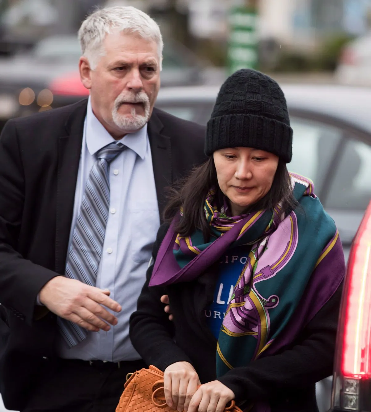 Huawei chief financial officer Meng Wanzhou (R) is escorted by a member of her private security detail while arriving at a parole office in Vancouver, Canada, on Dec. 12, 2018. (The Canadian Press/Darryl Dyck)
