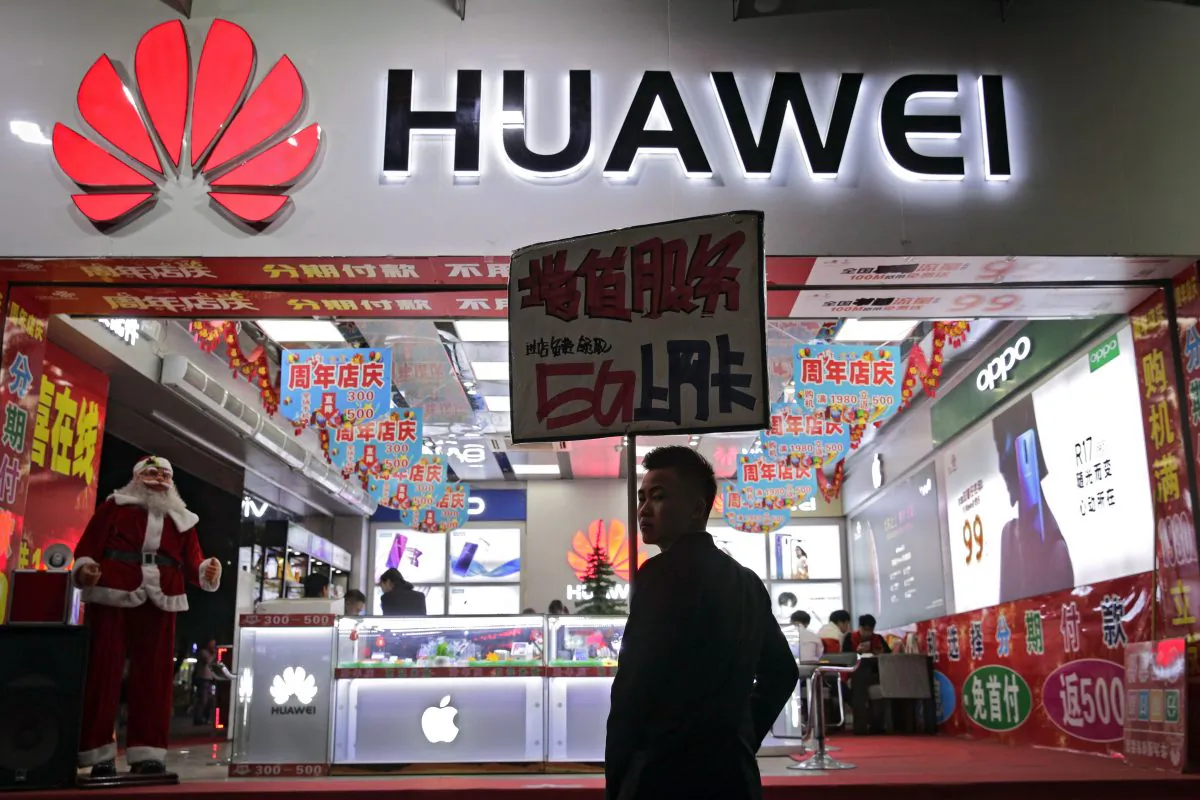 A worker holds a sign promoting a sale for Huawei 5G internet services at a mobile phone retail shop in Shenzhen, China, on Dec. 18, 2018. (AP Photo/Andy Wong)