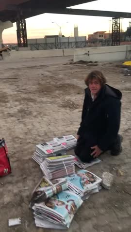 homeless man with newspapers