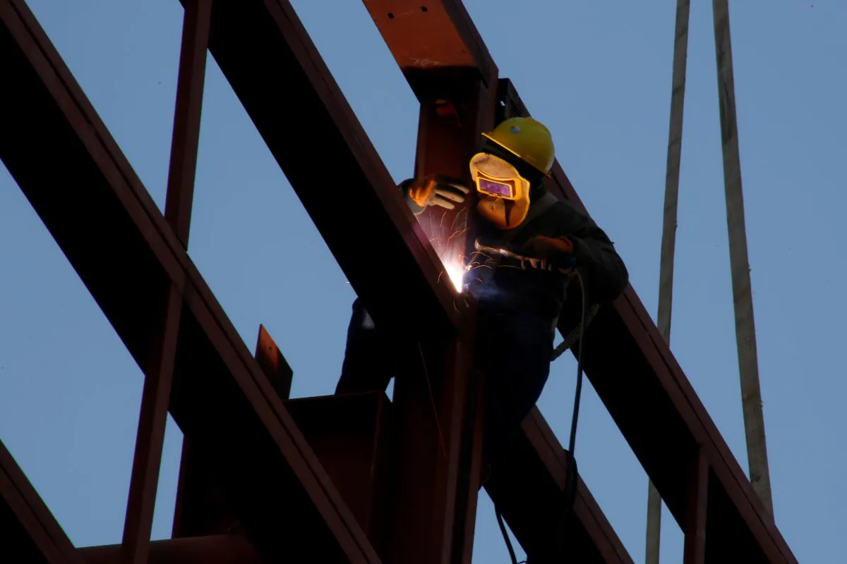 A worker welds as he stands on the metal frame of a building at a construction site in Beijing on Dec. 12, 2018. (Thomas Peter/Reuters)