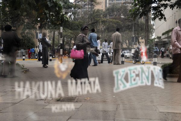 Kenyans walk past a store with a Hakuna Matata sign
