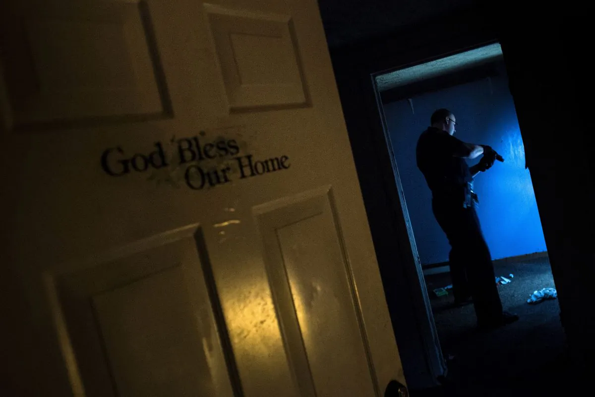 A police officer searches an abandoned house in Huntington, West Virginia on April 19, 2017. (BRENDAN SMIALOWSKI/AFP/Getty Images)