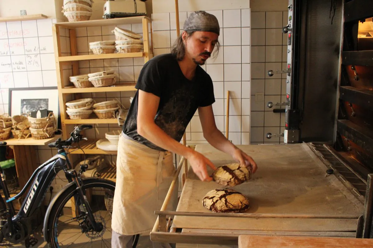 Maxime Bussy, owner and founder of Le Bricheton bakery in Paris, takes peasant chestnut bread out of the oven. (Alexia Luquet/Special to The Epoch Times)