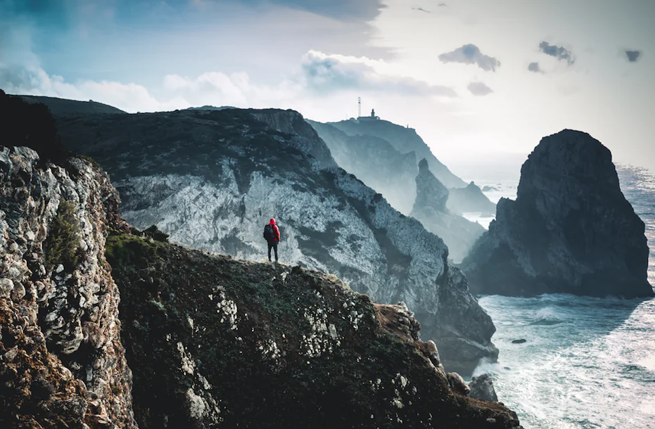 Walking on the edge of the land on a cloudy day, the ocean with big waves against the “walls”. (Unsplash)