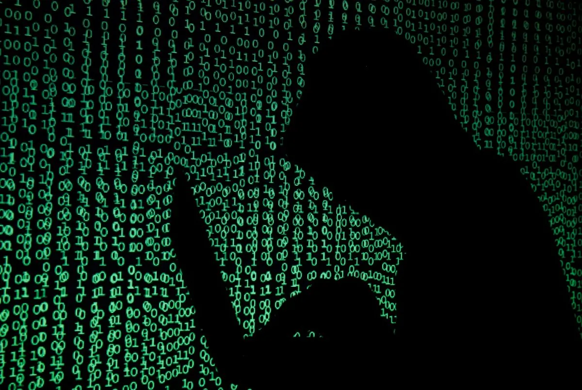 A hooded man holds a laptop computer as cyber code is projected on him in this illustration picture taken on May 13, 2017.  (Kacper Pempel/Illustration/Reuters)