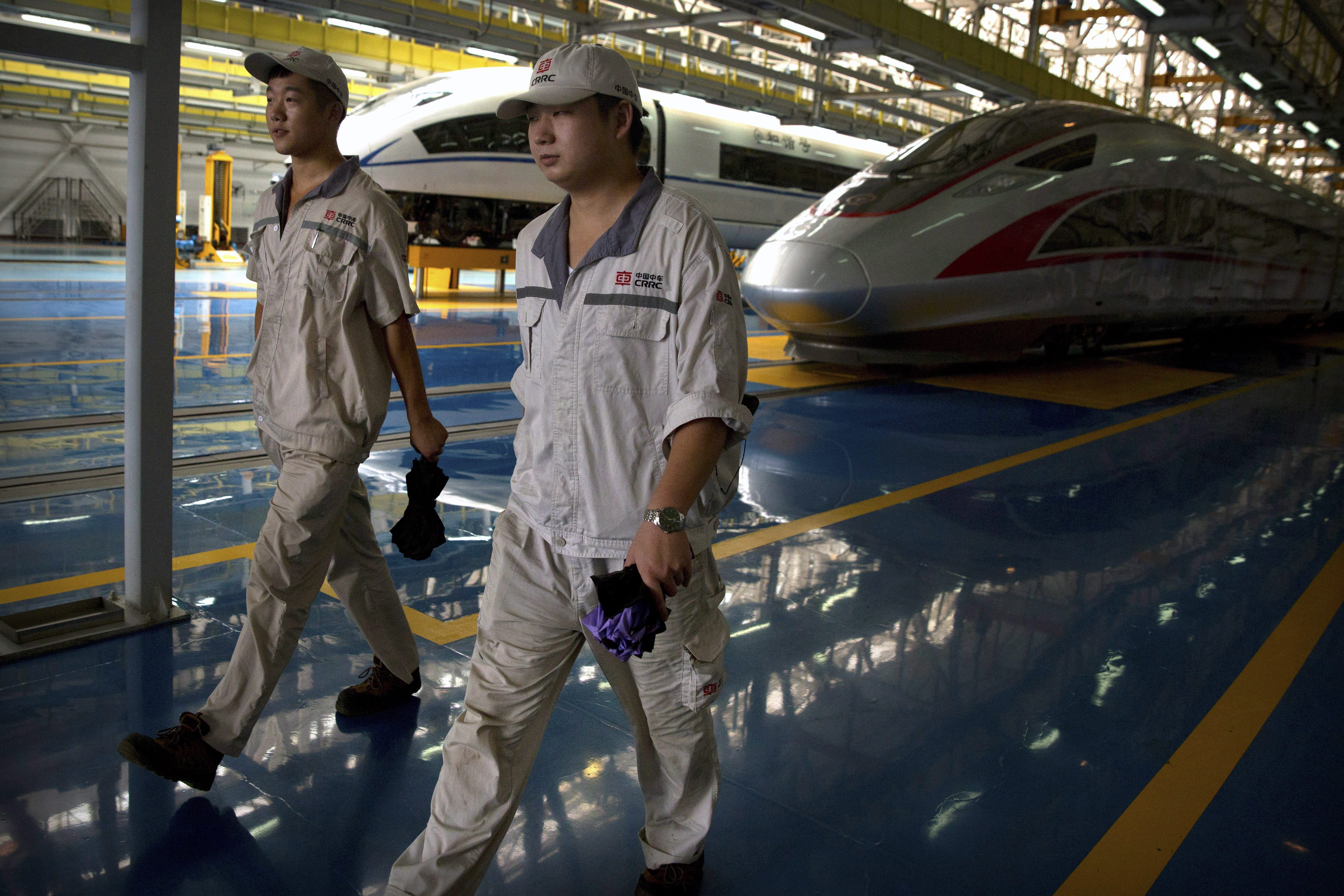 workers walk alongside the high speed trains