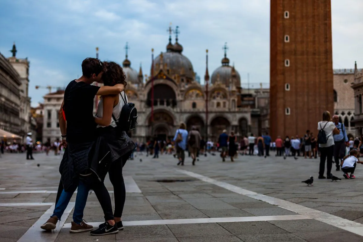 A couple of tourists kiss on St. Mark's Square, with the Italo-Byzantine Roman Catholic Saint Mark's Basilica in the background, in Venice, on Sept. 7, 2018. (Laurent Emmanuel/AFP/Getty Images)