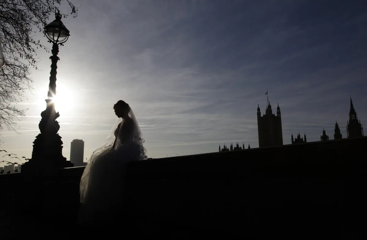A bride sits on a wall opposite the Houses of Parliament during a wedding photo shoot in central London on Jan. 6, 2012. (Reuters/Stefan Wermuth)