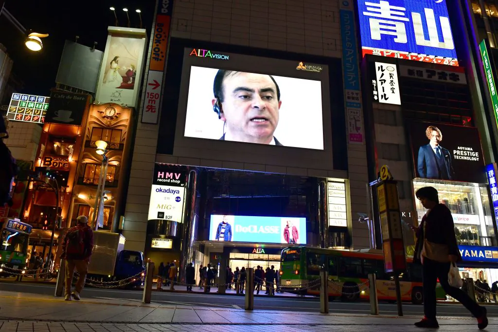A pedestrian walks past a screen showing a news programme featuring Nissan chairman Carlos Ghosn in Tokyo on Nov. 22, 2018. (Kazuhiro Nogi/AFP/Getty Images)