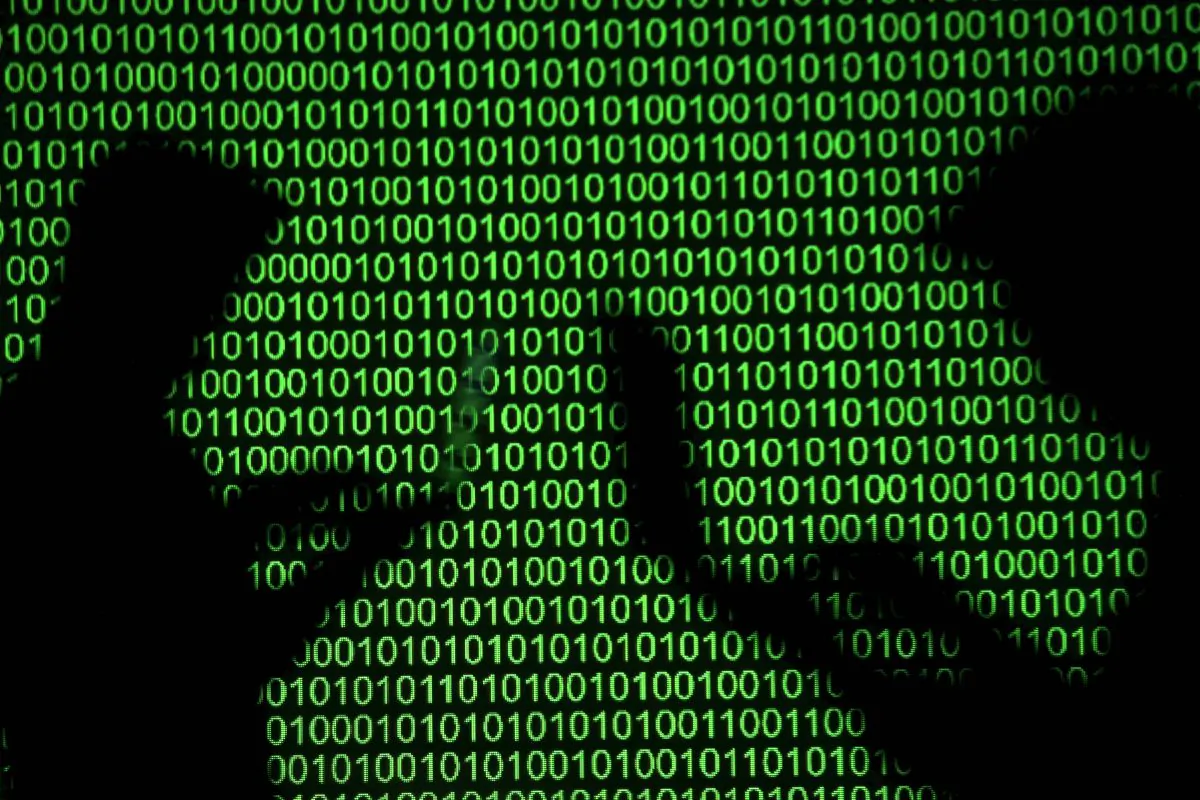 Silhouettes of laptop users next to a screen projection of binary code in this picture illustration taken on March 28, 2018. (Reuters/Dado Ruvic/Illustration/File Photo/File Photo)