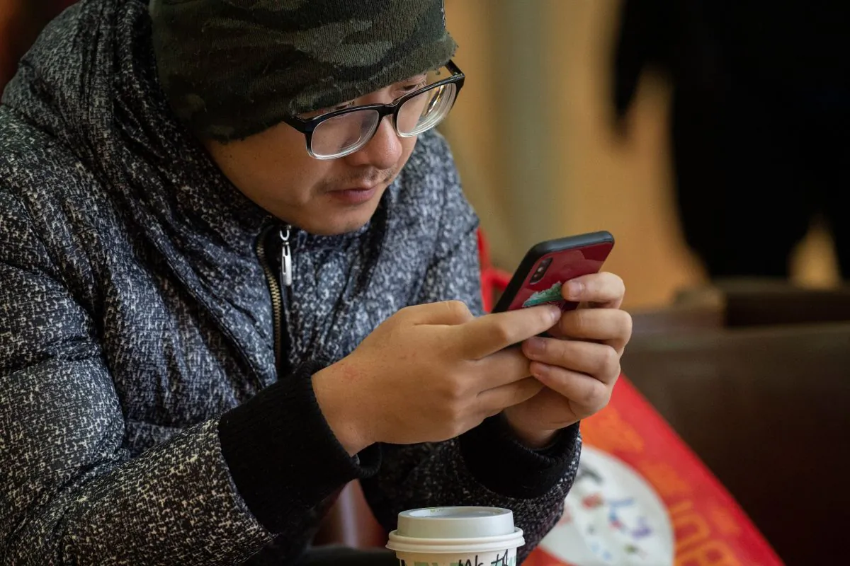 Two Chinese were punished in China after they had broken through the Internet censorship. The photo was took in Beijing on January 3, 2019 that a man was playing his smartphone.(NICOLAS ASFOURI/AFP/Getty Images)
