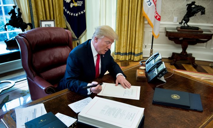 President Donald Trump signs the Tax Cut and Jobs Act in the Oval Office at the White House in Washington, on Dec. 22, 2017. (Brendan Smialowski/AFP/Getty Images)