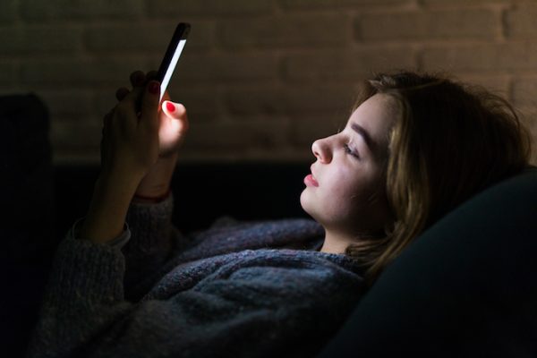 Young woman using smart phone at night in bed