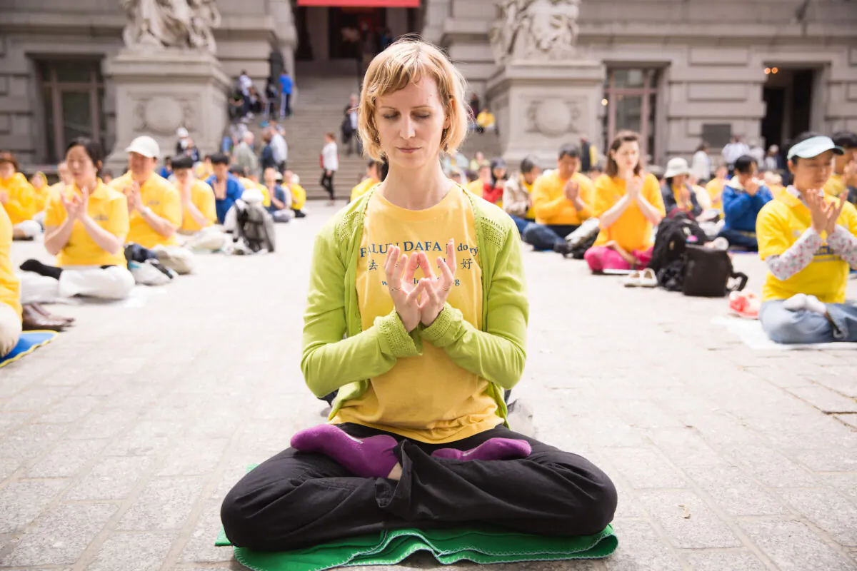 A woman who practices Falun Gong meditates with others near Battery Park in Manhattan during World Falun Dafa Day on May 13, 2015. (Laura Cooksey)