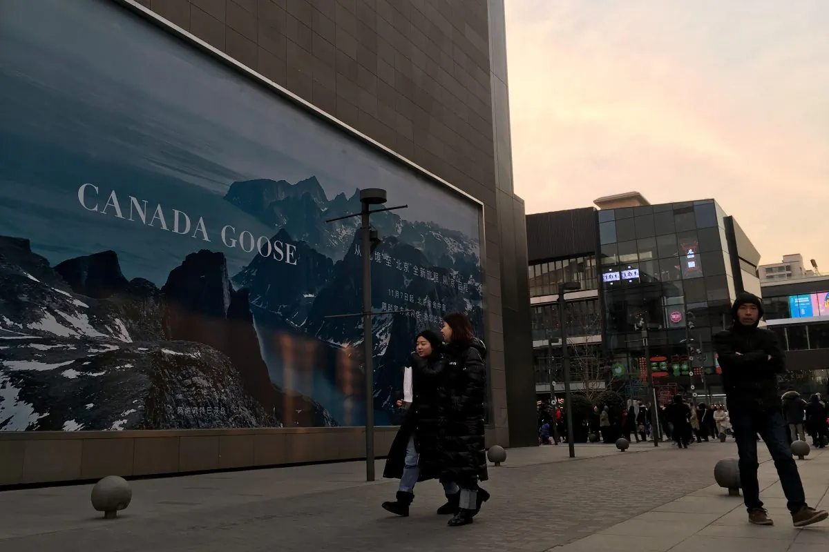 People walk past an advertisement near the newly opened flagship store of Canadian luxury parka maker Canada Goose, in the Sanlitun area of Beijing on December 31, 2018. (REUTERS/Martin Pollard)