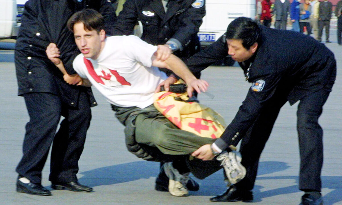 Chinese police officers take away a Canadian Falun Gong practitioner after he participated in a peaceful protest on Tiananmen Square in November 2001. (Ng Han Guan/AP Photo)