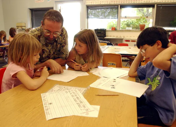 Substitute teacher, Andy McCain, helps first grade students. BOULDER,CO. ON MAY 24TH 2004. (Andy Cross/The Denver Post via Getty Images)