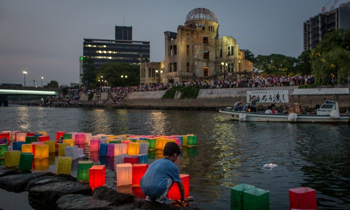 A boy floats a candle lit paper lantern on the river in front of the Atomic Bomb Dome  during 70th anniversary activities, commemorating the atomic bombing of Hiroshima at the Hiroshima Peace Memorial Park in Hiroshima, Japan, on Aug. 6, 2015. The bomb instantly killed an estimated 70,000 people and thousands more in coming years from radiation effects. Three days later, the United States dropped a second atomic bomb on Nagasaki which ended World War II.  (Chris McGrath/Getty Images)