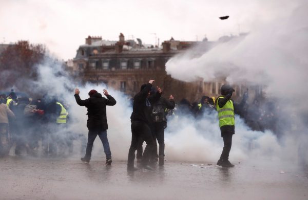 Protesters walk through tear gas during a demonstration of the "yellow vests" movement near the Arc de Triomphe in Paris