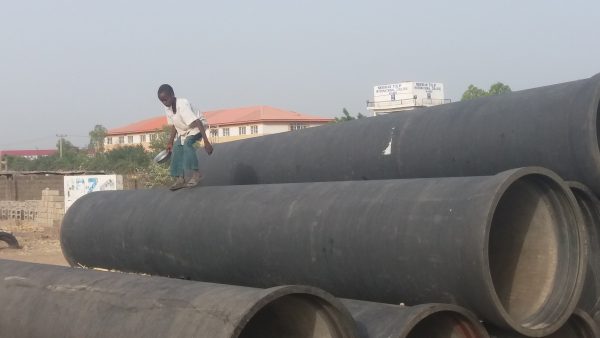 An Almajiri child plays on abandoned water pipes in Kano, Nigeria, on Nov. 11, 2016. (Toluwani Eniola/Special to The Epoch Times)