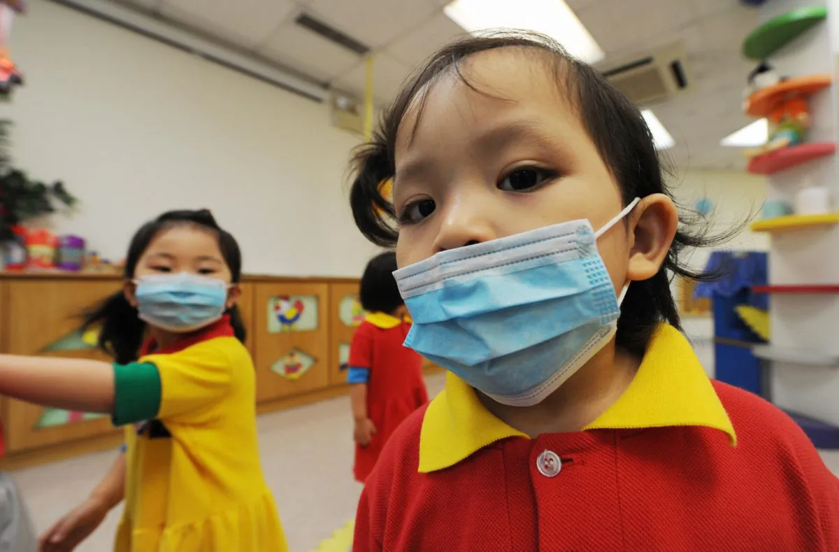 Masked children play at a kindergarten situated inside a residential estate in Hong Kong on June 11, 2009. (MIKE CLARKE/AFP/Getty Images)
