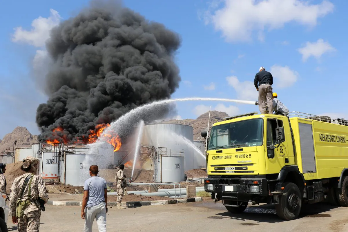 Firefighters try to cool down oil storage tanks adjacent to a tank engulfed by fire at the Aden oil refinery in Aden, Yemen, on Jan. 12, 2019. (Reuters/Fawaz Salman)
