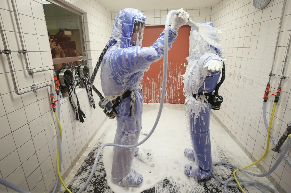 A nurse and a doctor for tropical medicine wearing isolation suits demonstrate the decontamination procedure as part of ebola treatment capability at Station 59 at Charite hospital on Aug. 11, 2014 in Berlin, Germany. (Sean Gallup/Getty Images)