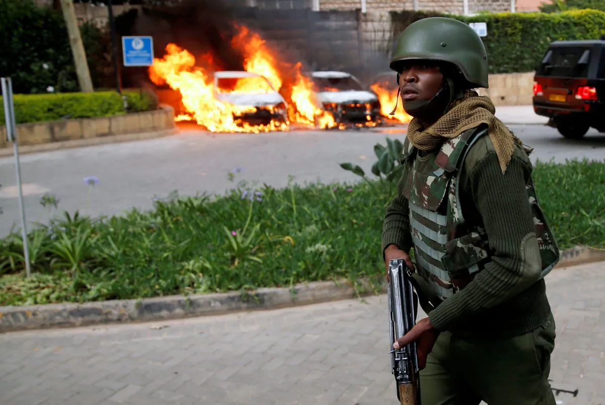A policeman runs past burning cars at the scene where explosions and gunshots were heard at the Dusit D2 hotel compound, in Nairobi, Kenya, Jan. 15, 2019. (Reuters Baz Ratner)