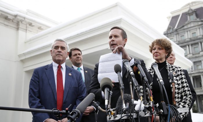 Rep. Rodney Davis, (R-Ill.), center, holds up a paper about President Donald Trump's proposals for the border, as he and other House Republicans speak to the media, Tuesday, Jan. 15, 2019, after meeting with the president at the White House on border security. (AP Photo/Jacquelyn Martin)