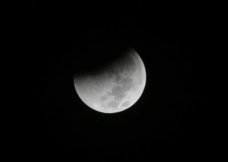 In this Saturday Aug. 28, 2018 file photo, Earth starts to cast its shadow on the moon during a complete lunar eclipse seen from Jakarta, Indonesia. (AP Photo/Tatan Syuflana)